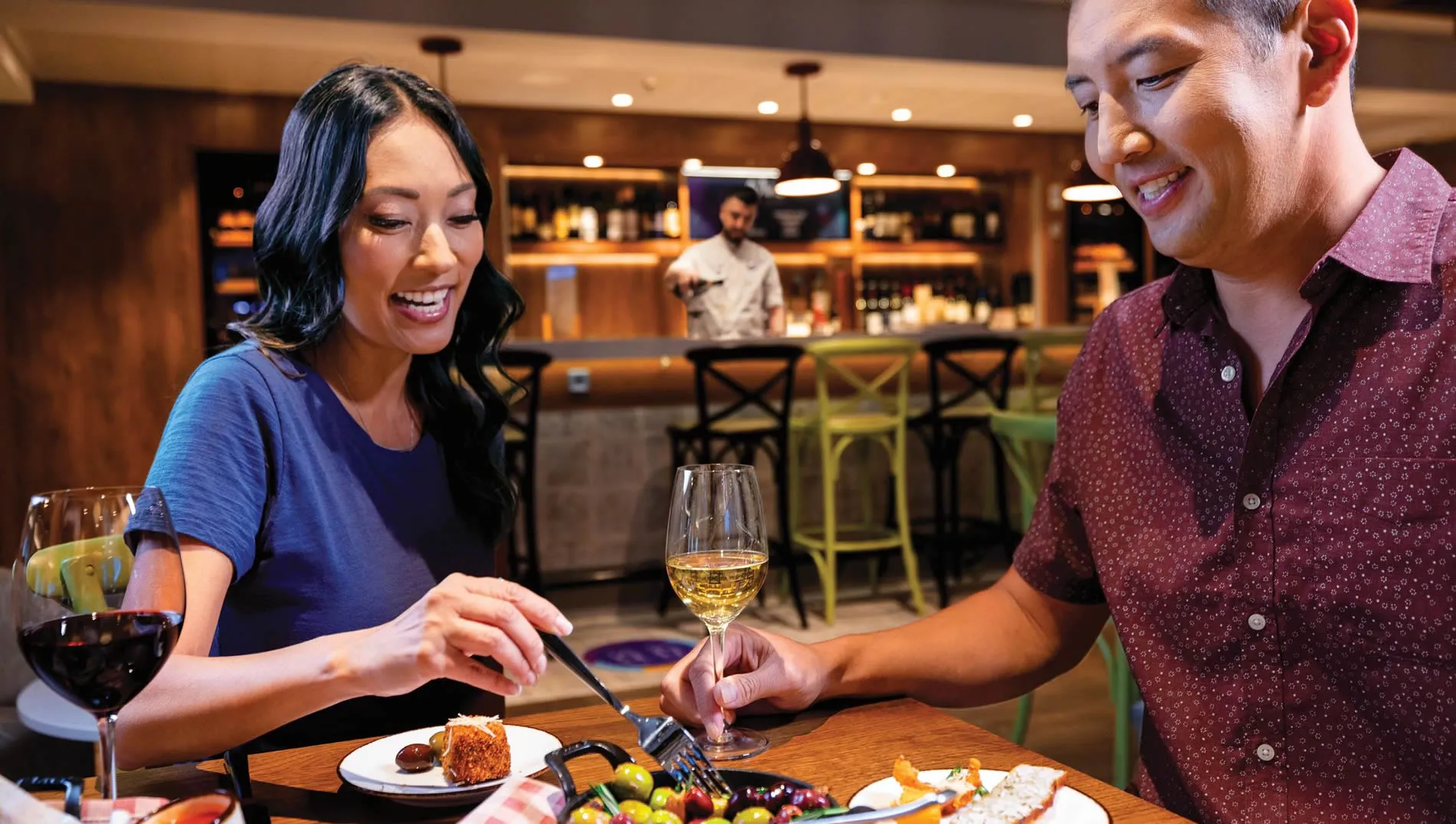 Couple enjoying wine and appetizers together at a cozy restaurant bar