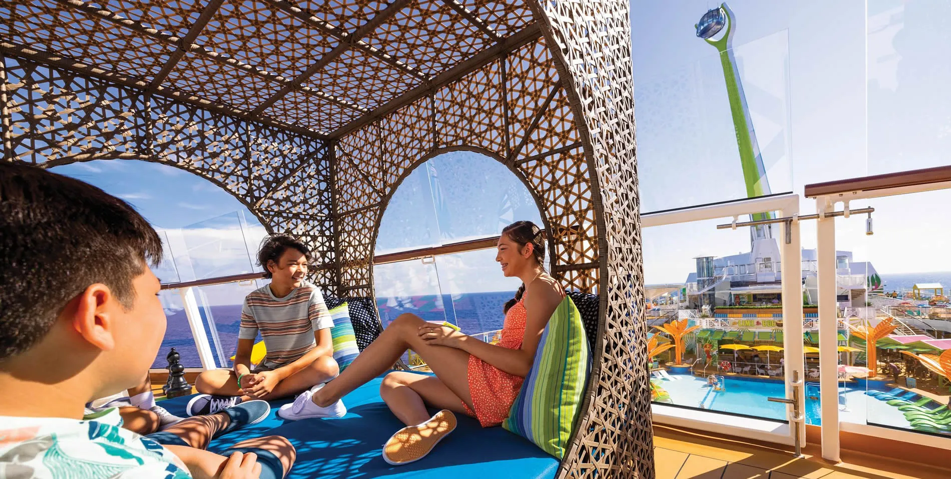Cruise ship deck with kids relaxing in woven shade structure overlooking pool