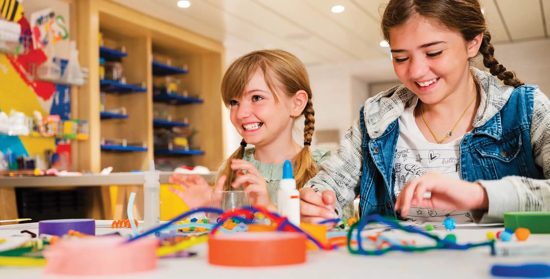 Students smiling while working on colorful craft project together