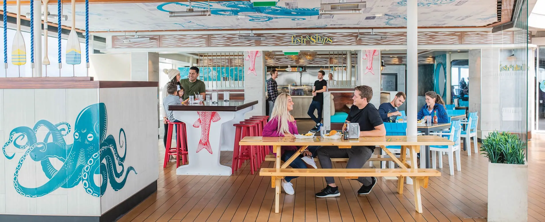 Nautical-themed restaurant with octopus mural and people dining