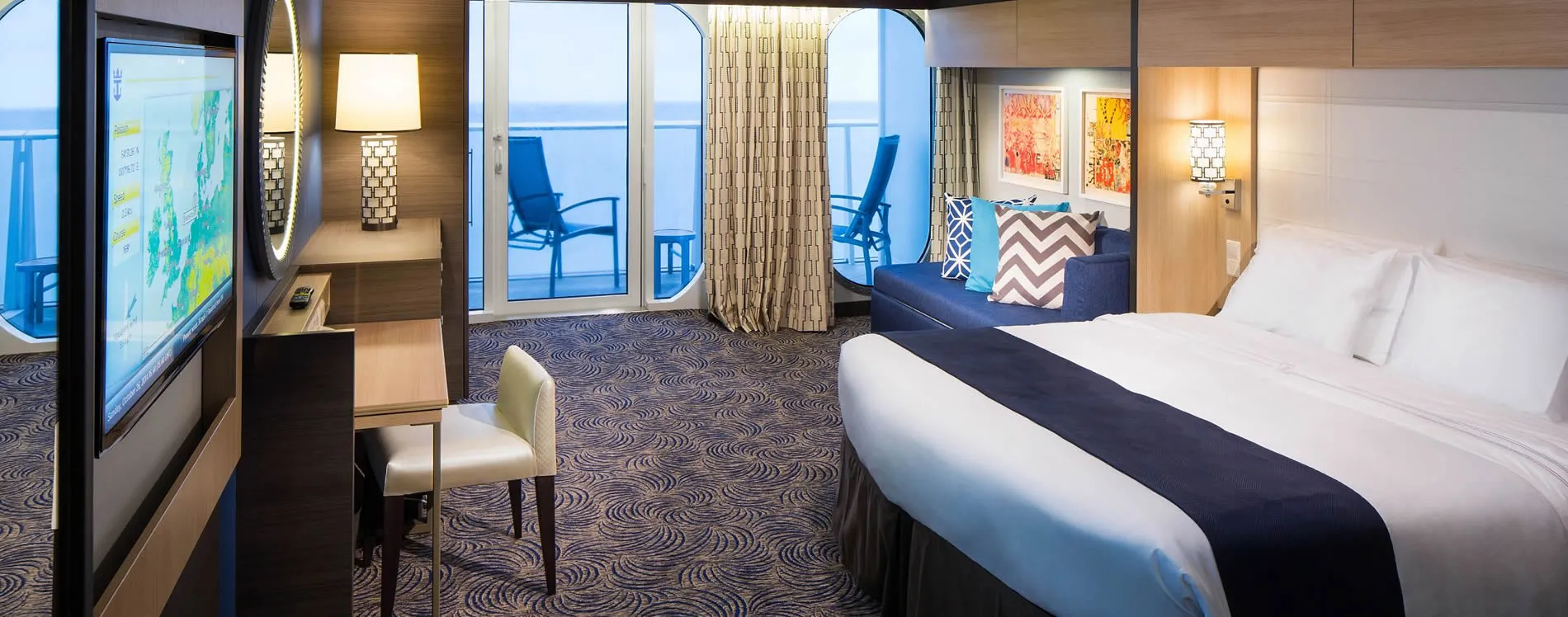 Modern cruise ship cabin with ocean view, bed, and balcony