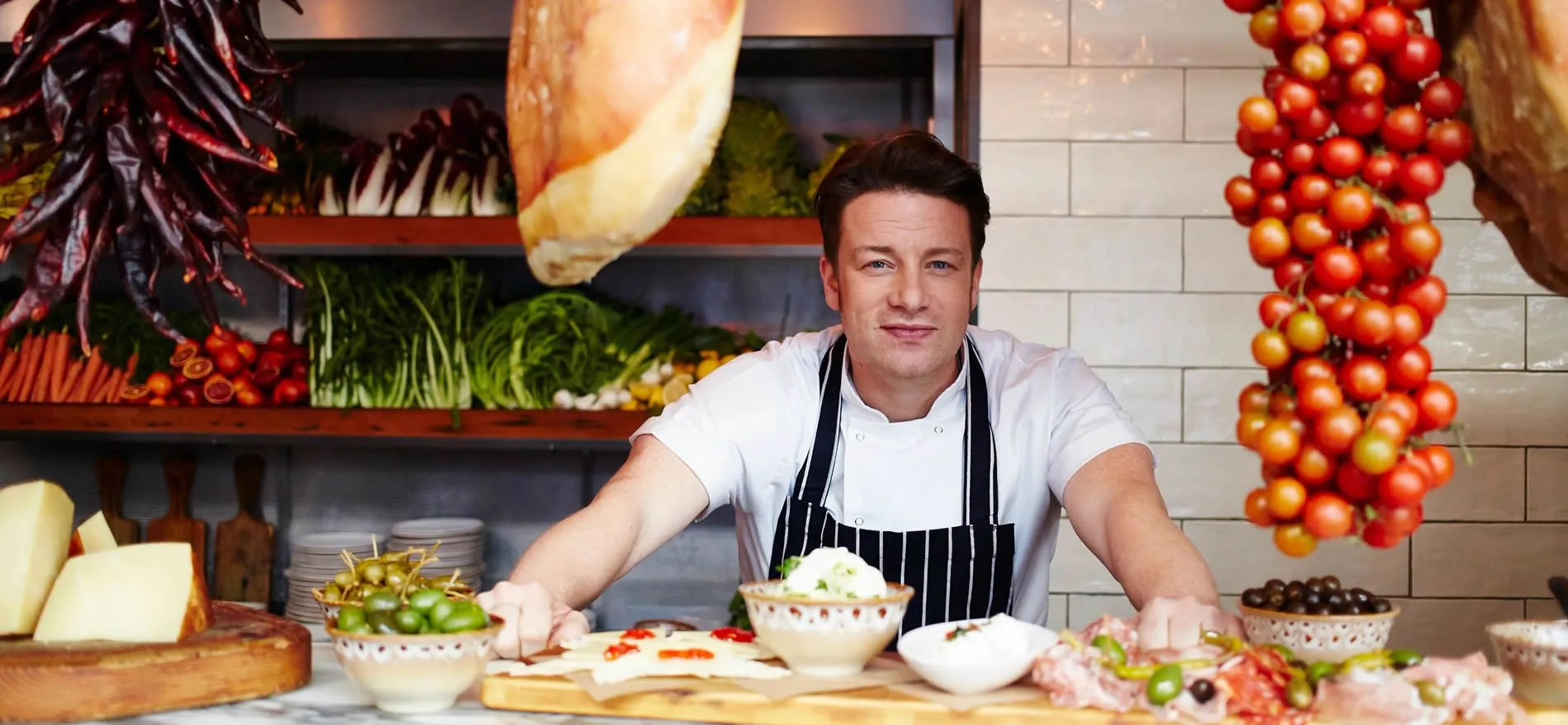 Chef in kitchen surrounded by fresh ingredients and cooking supplies