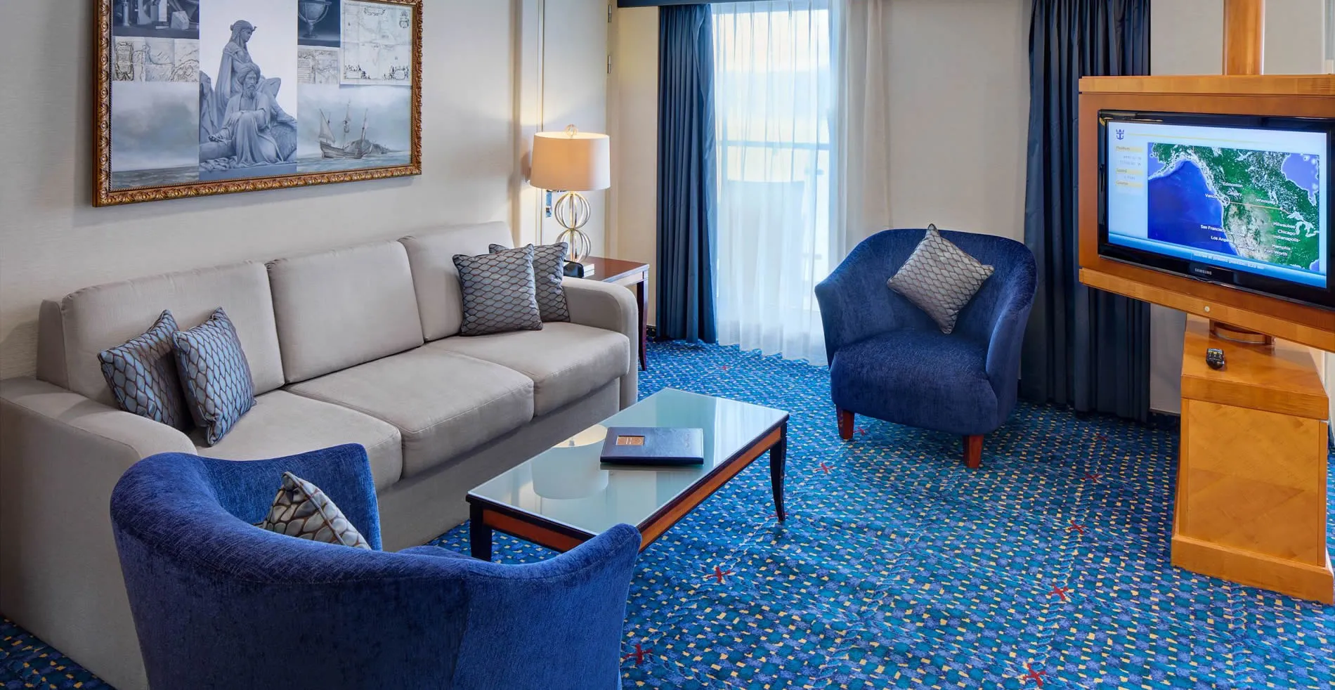 Cozy hotel suite with blue armchairs, gray sofa, and nautical artwork