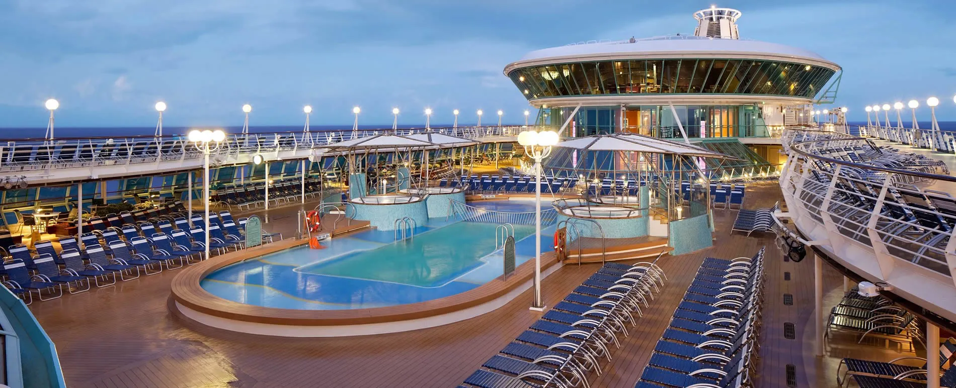 Luxurious cruise ship deck with swimming pool and lounge chairs at twilight