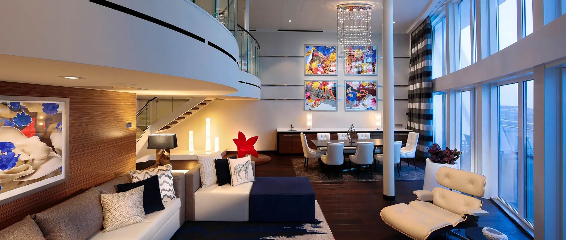 Modern two-story living space with colorful art, curved glass, and designer furniture