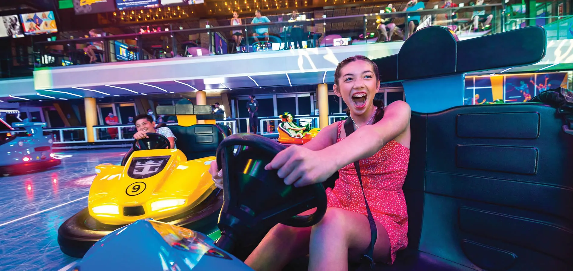 Excited woman driving bumper car with bright yellow lights in arcade