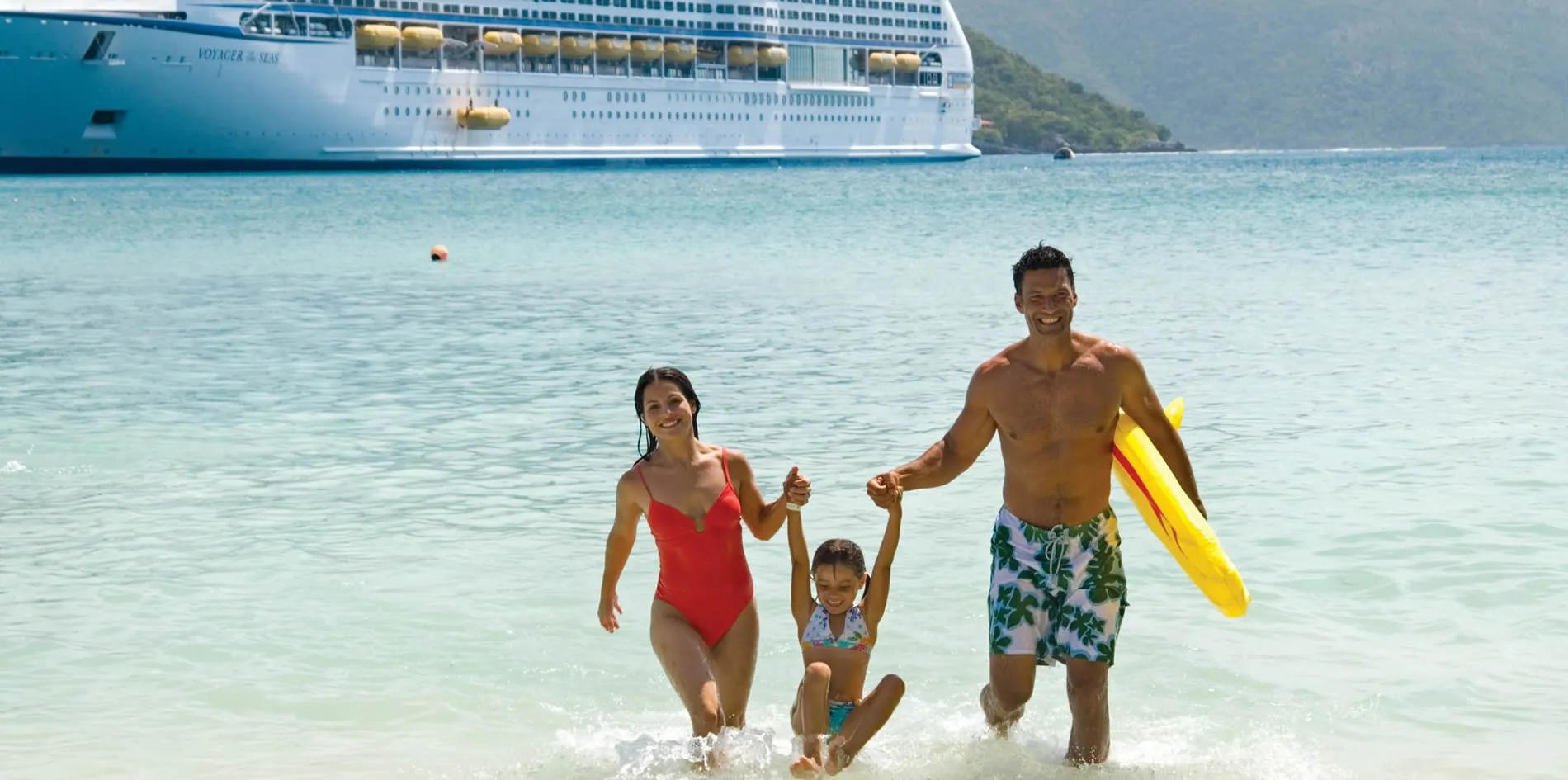 Family enjoying beach with cruise ship, holding hands and splashing