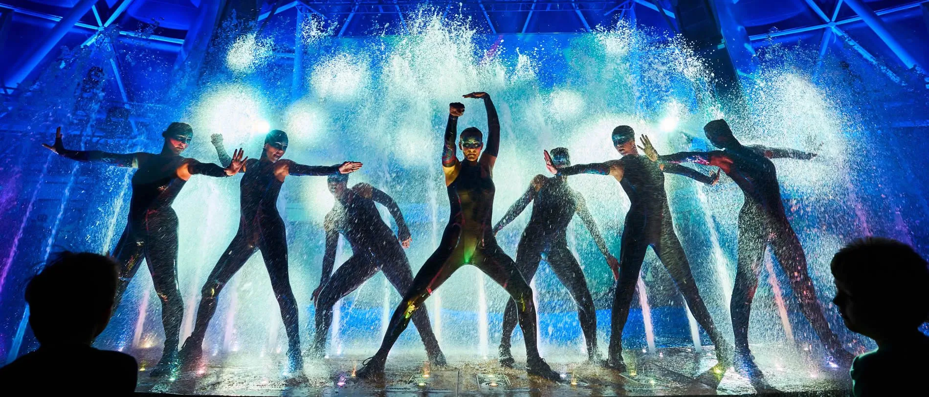 Dancers performing synchronized water dance with dramatic blue lighting