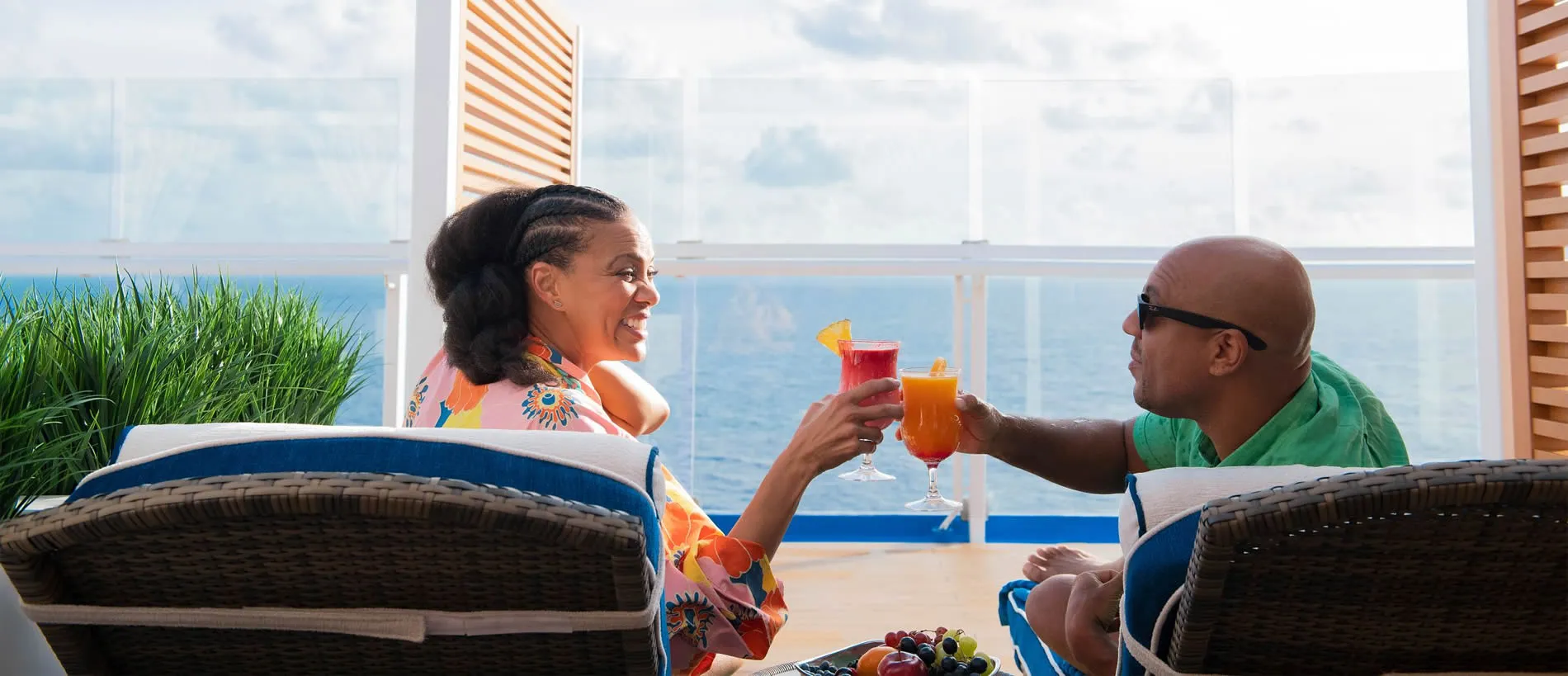Couple toasting tropical drinks on cruise ship balcony with ocean view