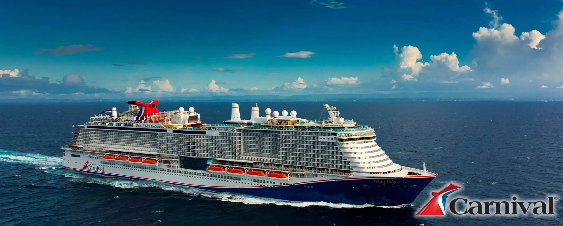 Large Carnival cruise ship sailing on blue ocean with white clouds