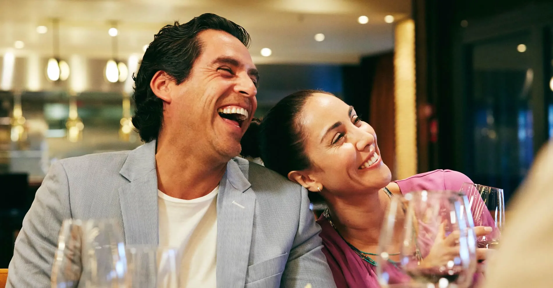 Two people laughing together while having drinks in a restaurant