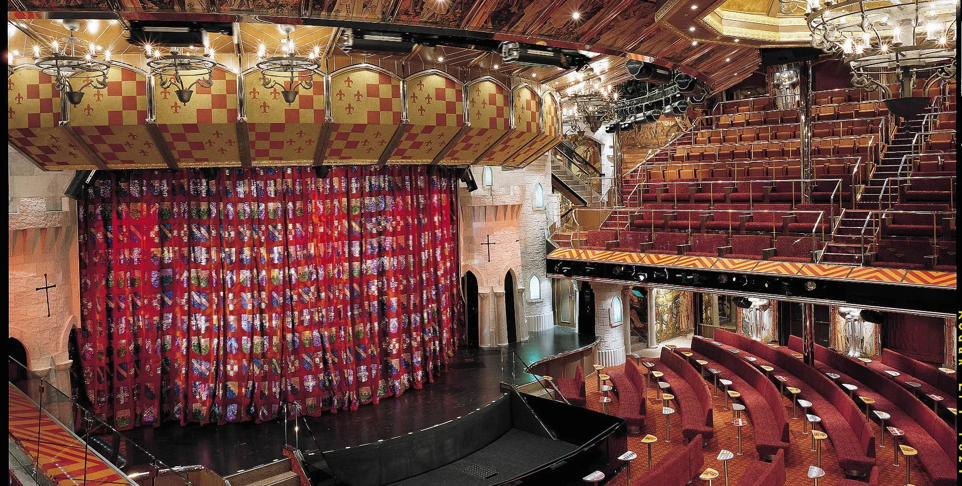 Ornate theater interior with red curtain, wooden ceiling, and tiered seating