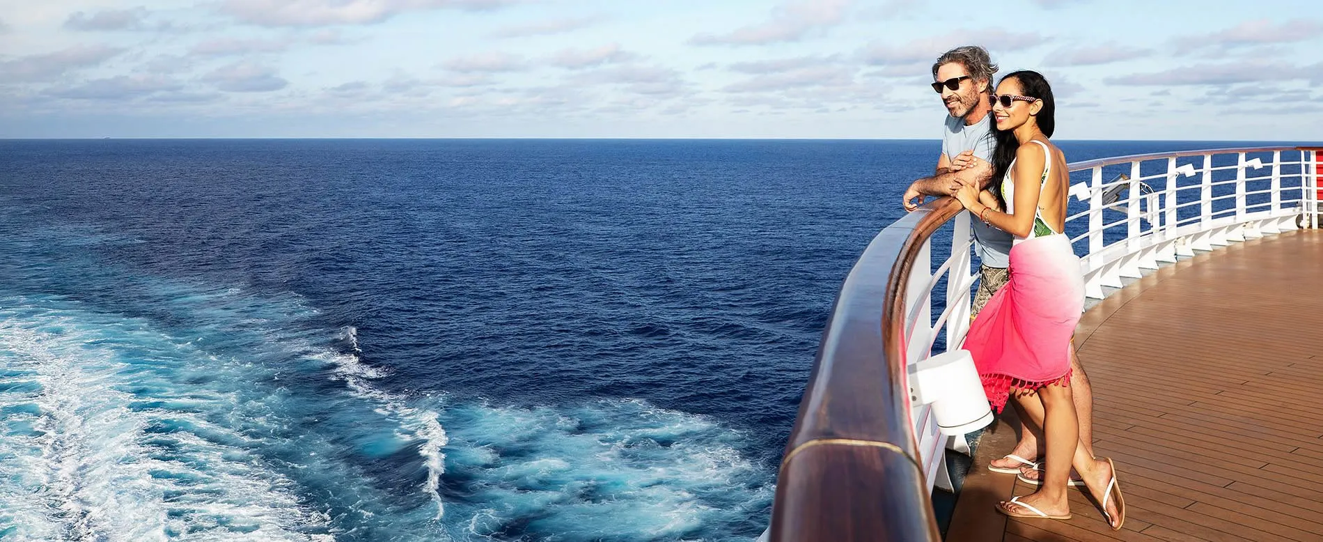 Couple enjoying cruise vacation, standing on deck overlooking ocean waves