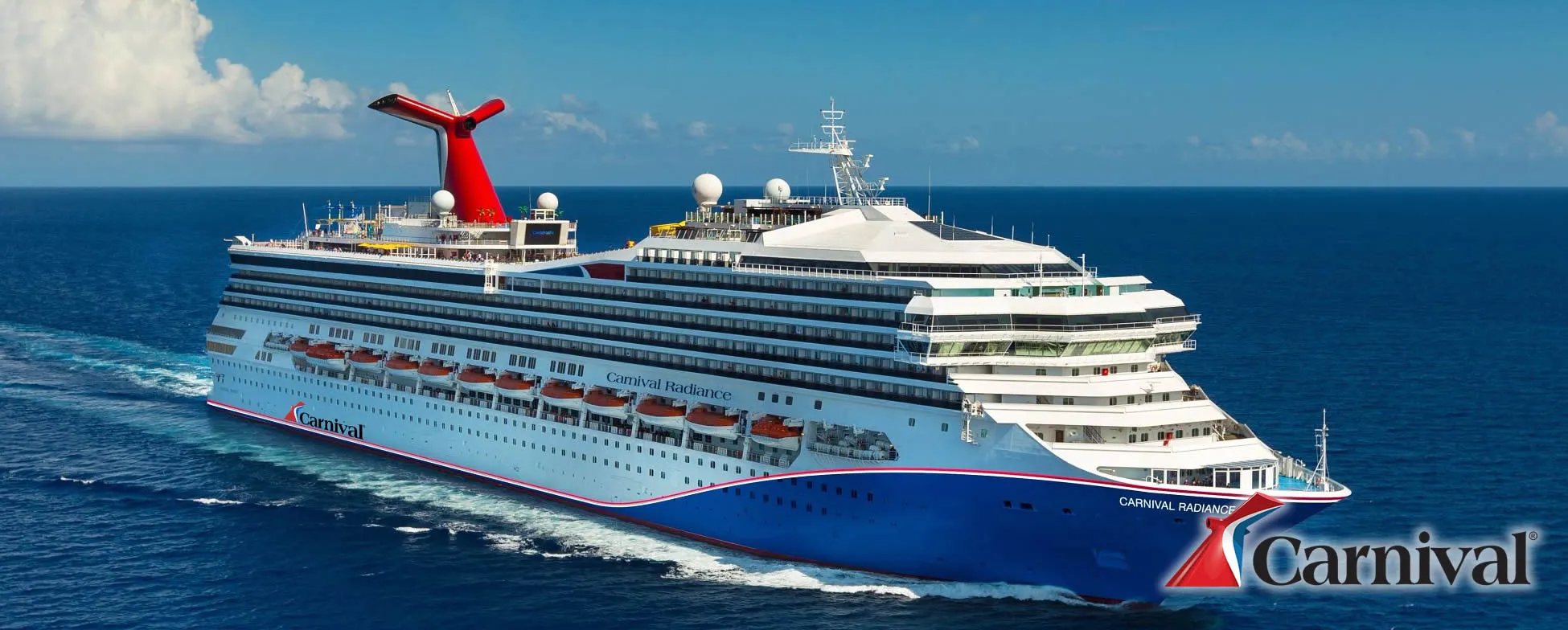 Carnival Radiance cruise ship sailing on blue ocean with white clouds