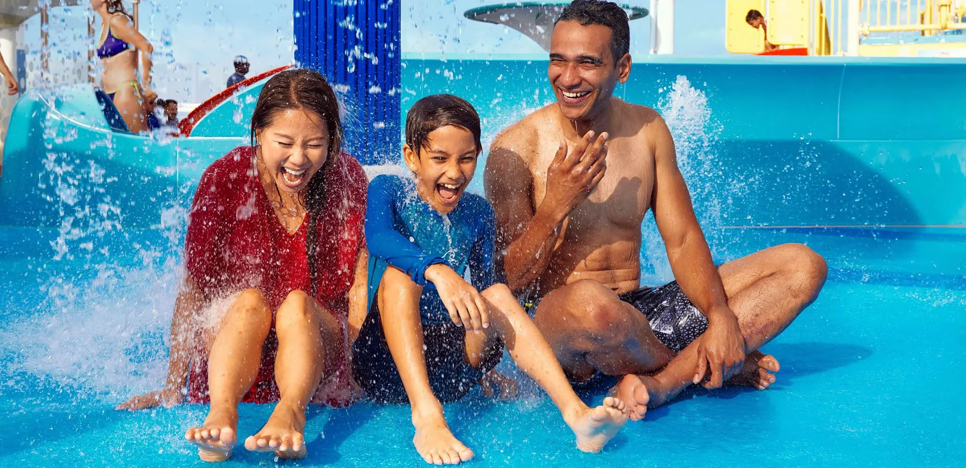 Family laughing and playing together in a water park splash zone