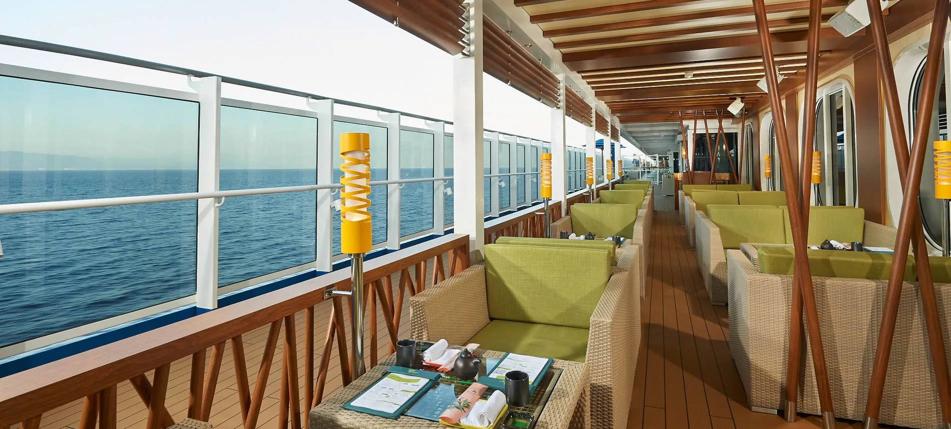 Cruise ship deck with green chairs, ocean view, and wooden elements