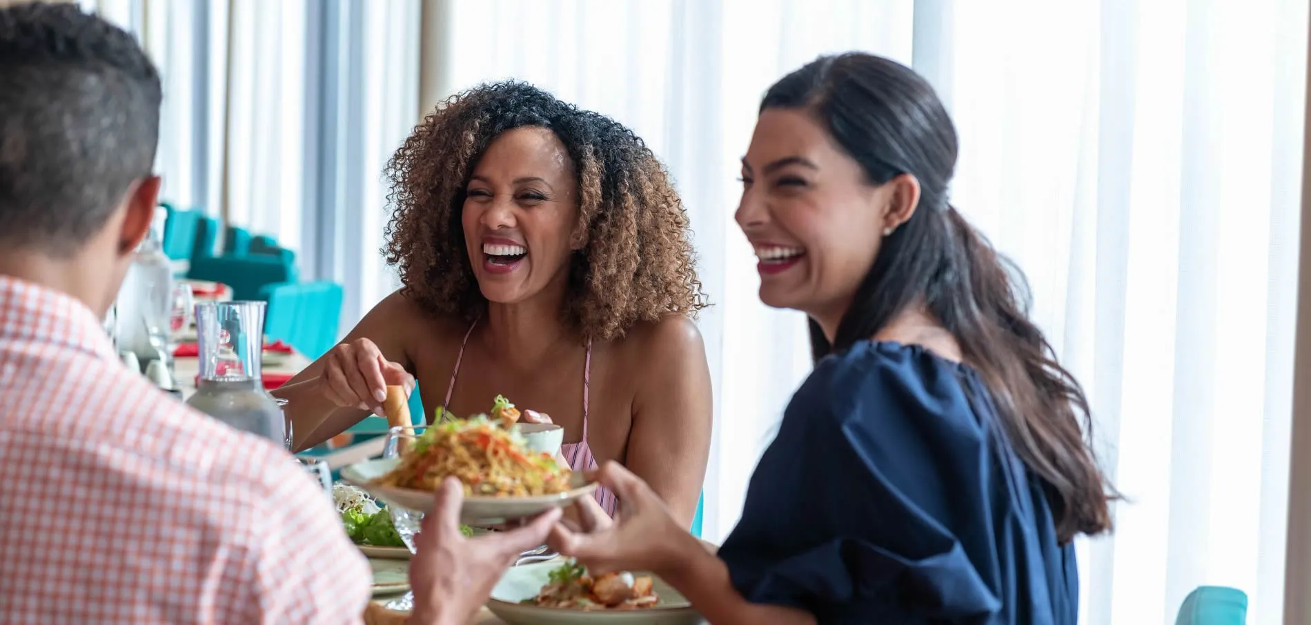 Friends laughing and enjoying a meal together at a dining table
