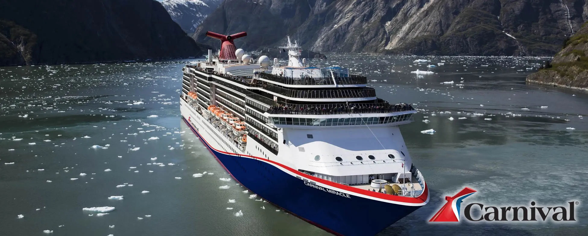 Carnival cruise ship sailing through icy fjord with snow-capped mountains