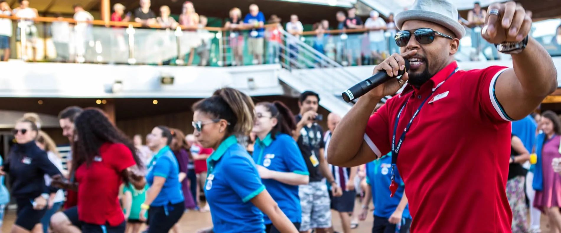 Entertainer in red shirt speaking into microphone at crowded event
