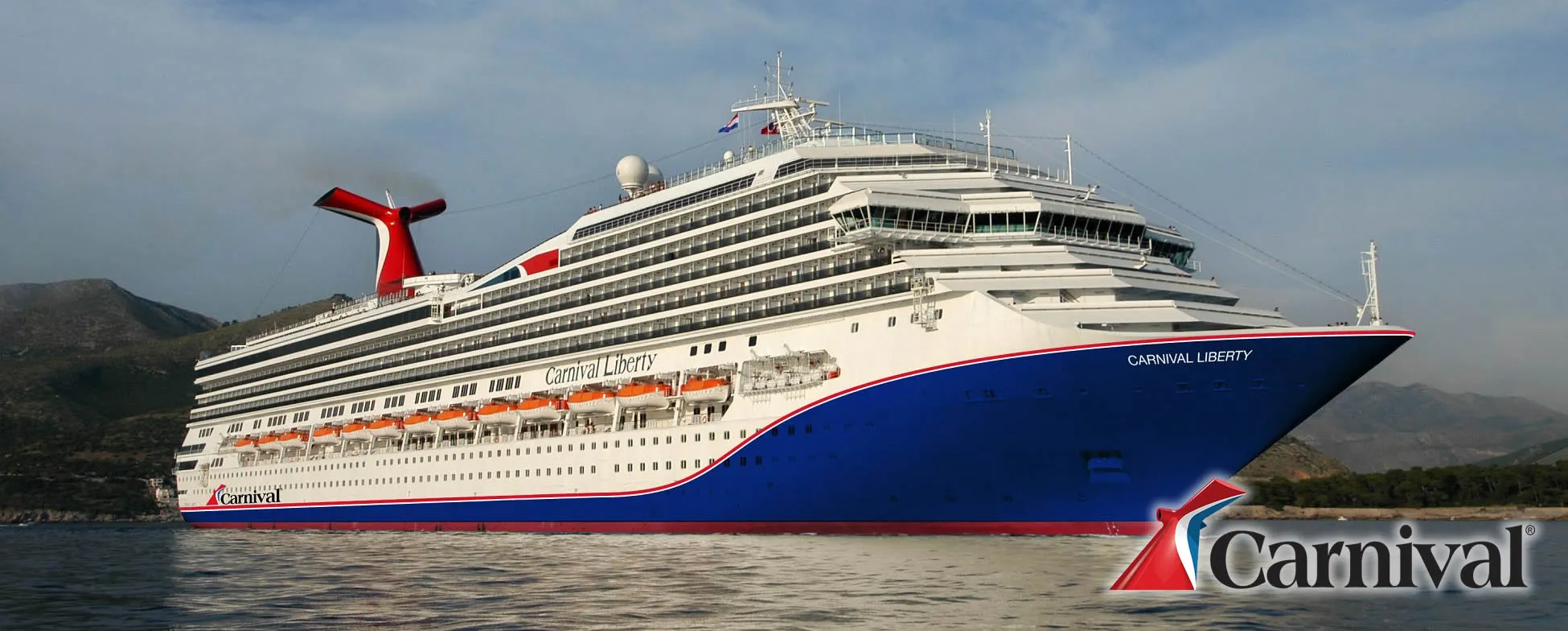 Carnival Liberty cruise ship sailing near mountains with blue and red colors