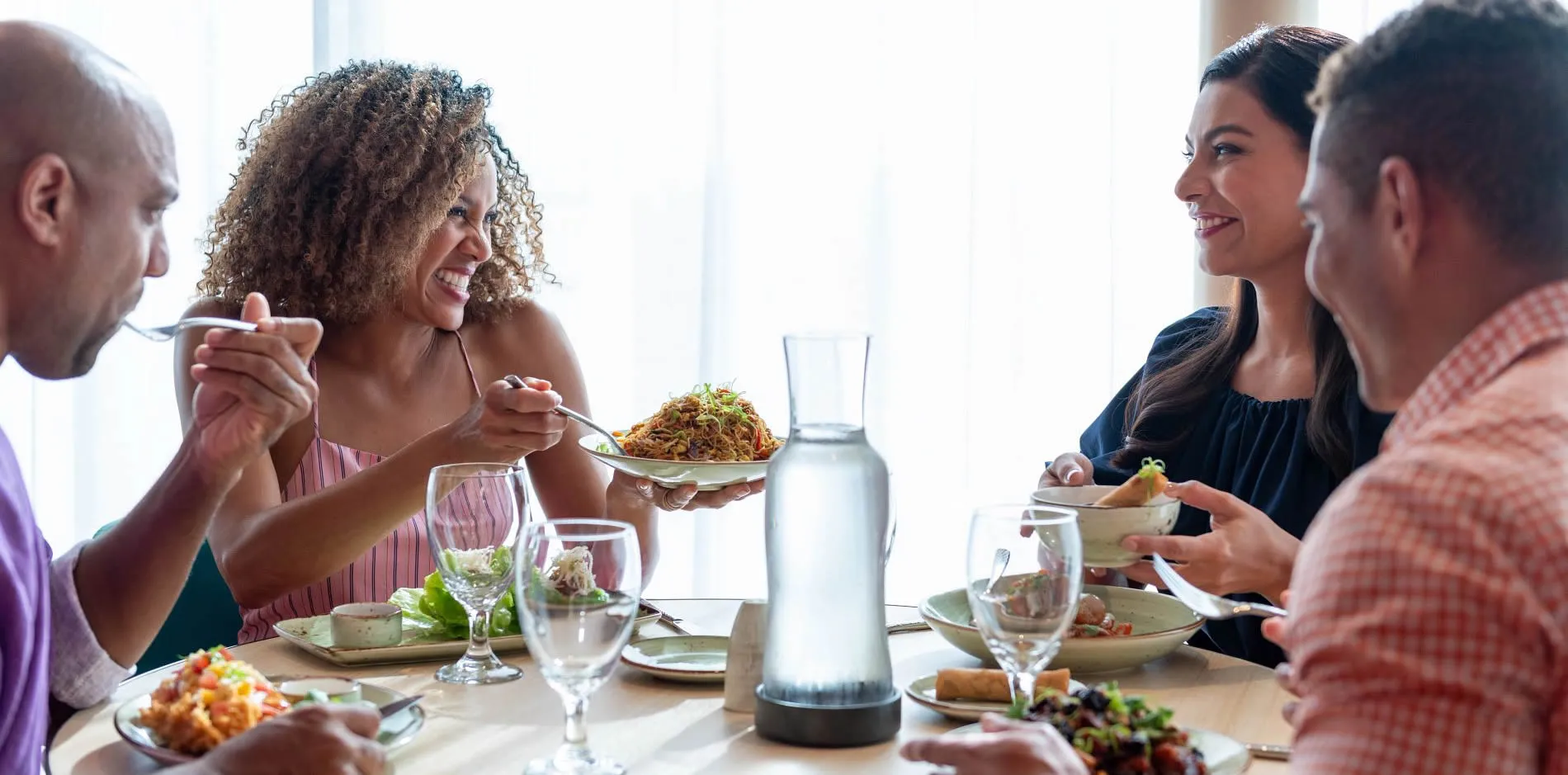 Friends enjoying a meal together, laughing and sharing food at table