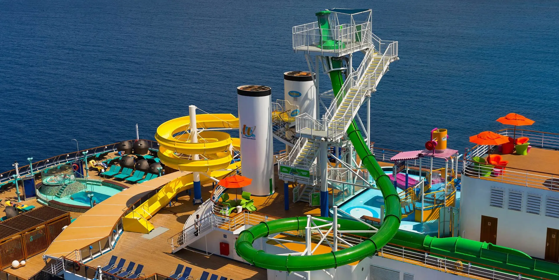 Colorful water slides and pools on a cruise ship deck over blue ocean