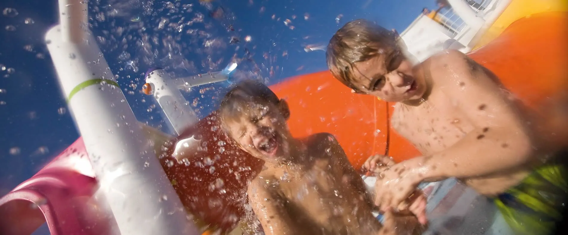 Children splashing and playing on a water slide on a sunny day