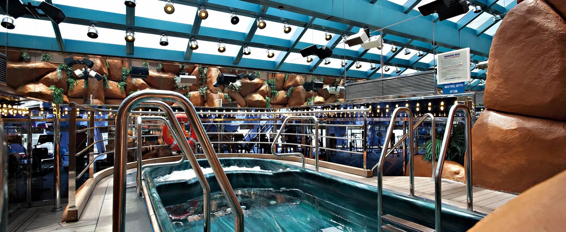 Indoor cruise ship pool with glass ceiling and decorative brown sculptures