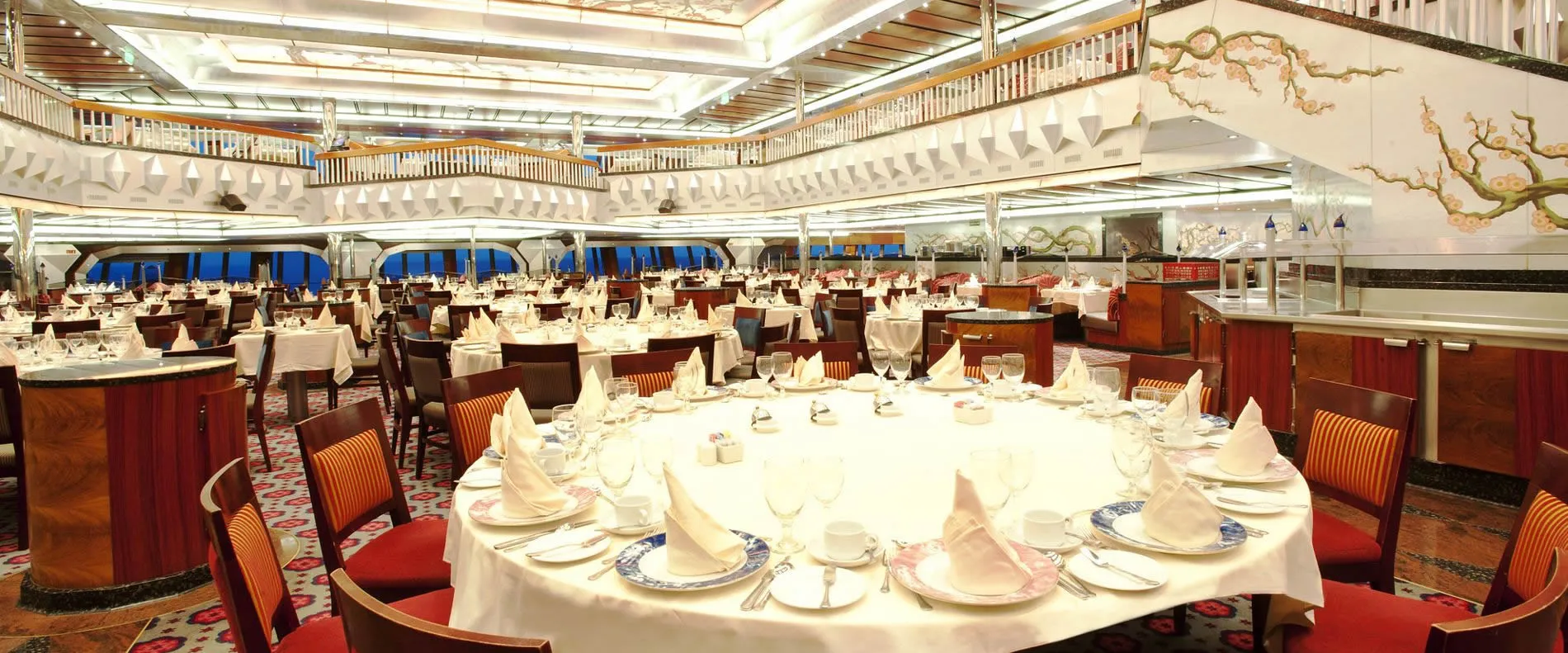 Elegant cruise ship dining room with white-clothed tables and large windows