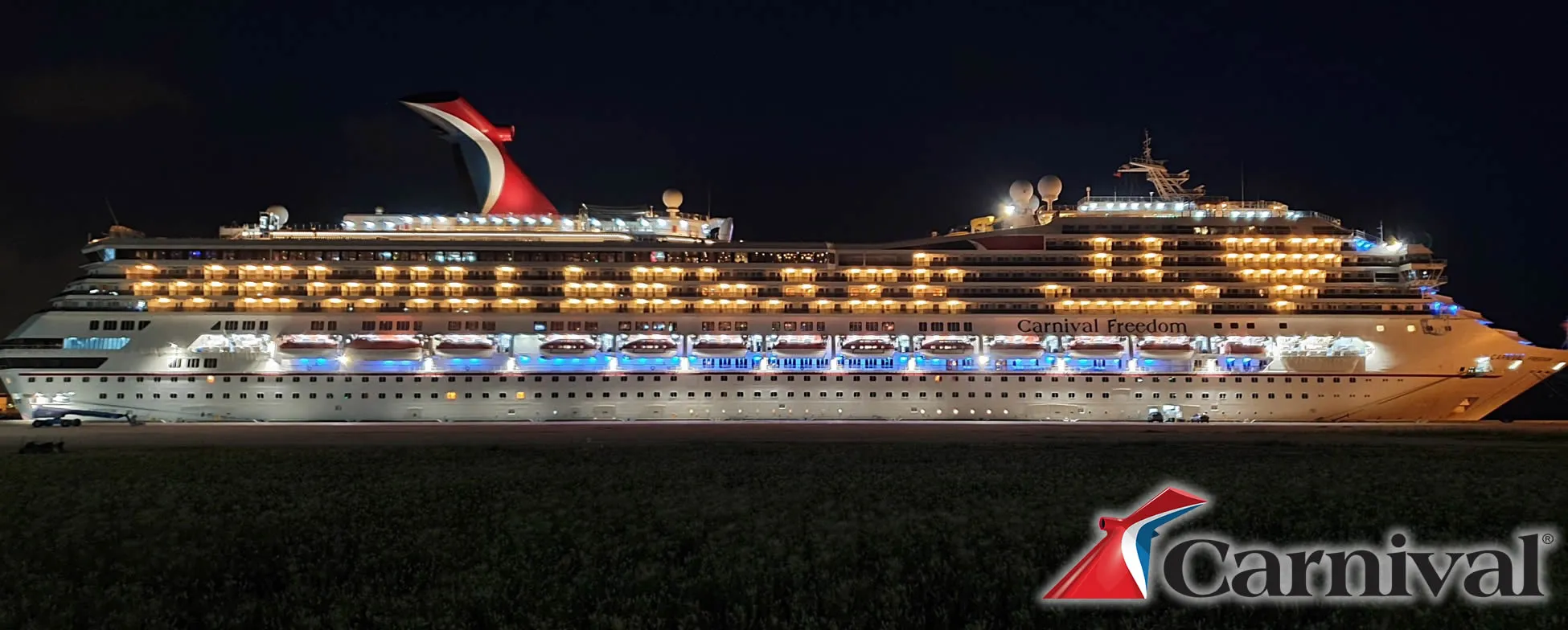 Carnival Freedom cruise ship illuminated at night with colorful lights
