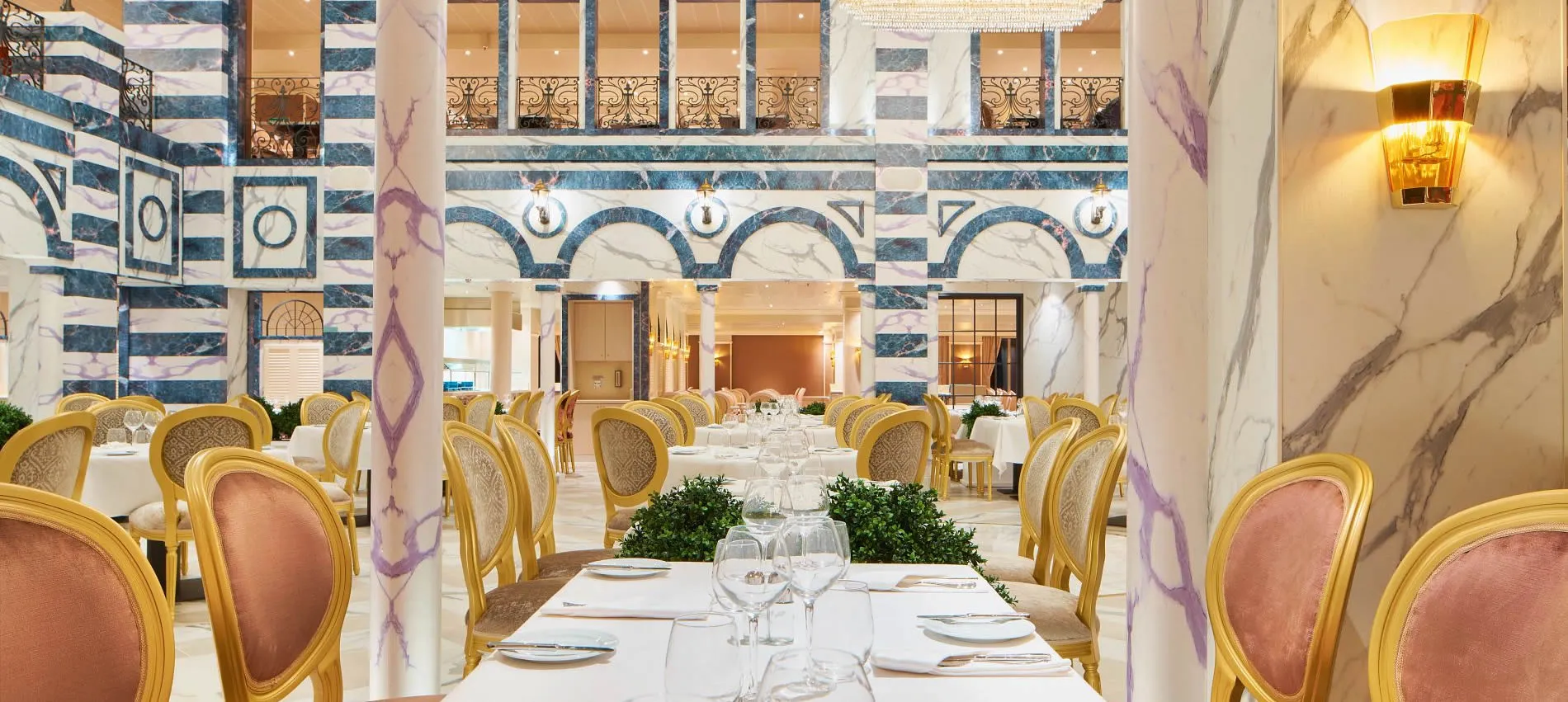 Elegant marble restaurant interior with gold chairs and white tablecloths