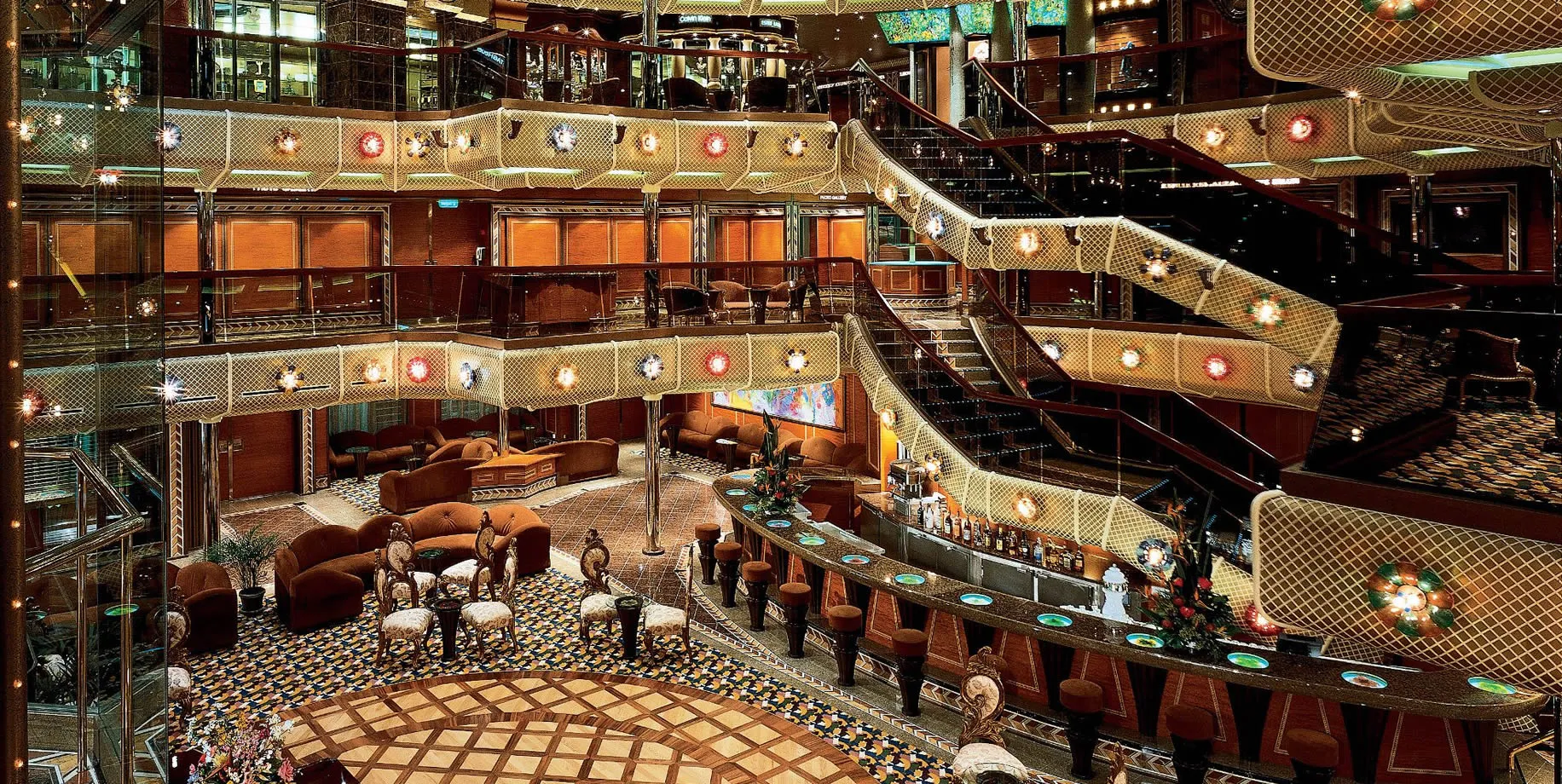 Luxurious multi-level cruise ship lounge with ornate lighting and curved bar