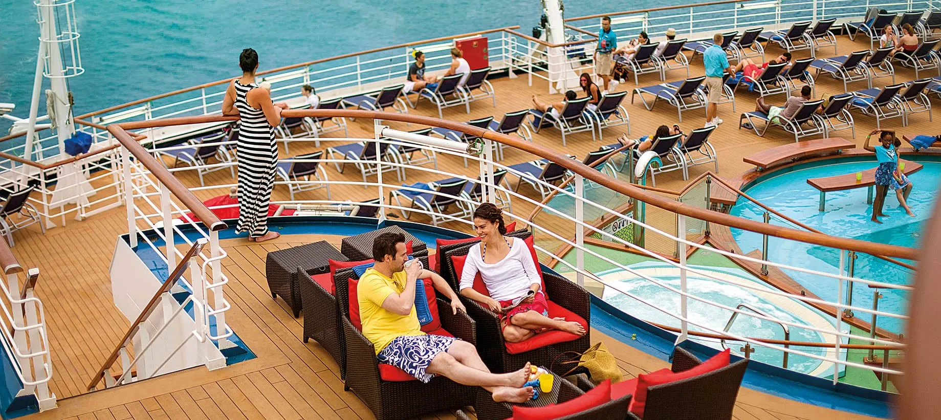 Cruise ship deck with passengers relaxing by pool and lounge chairs