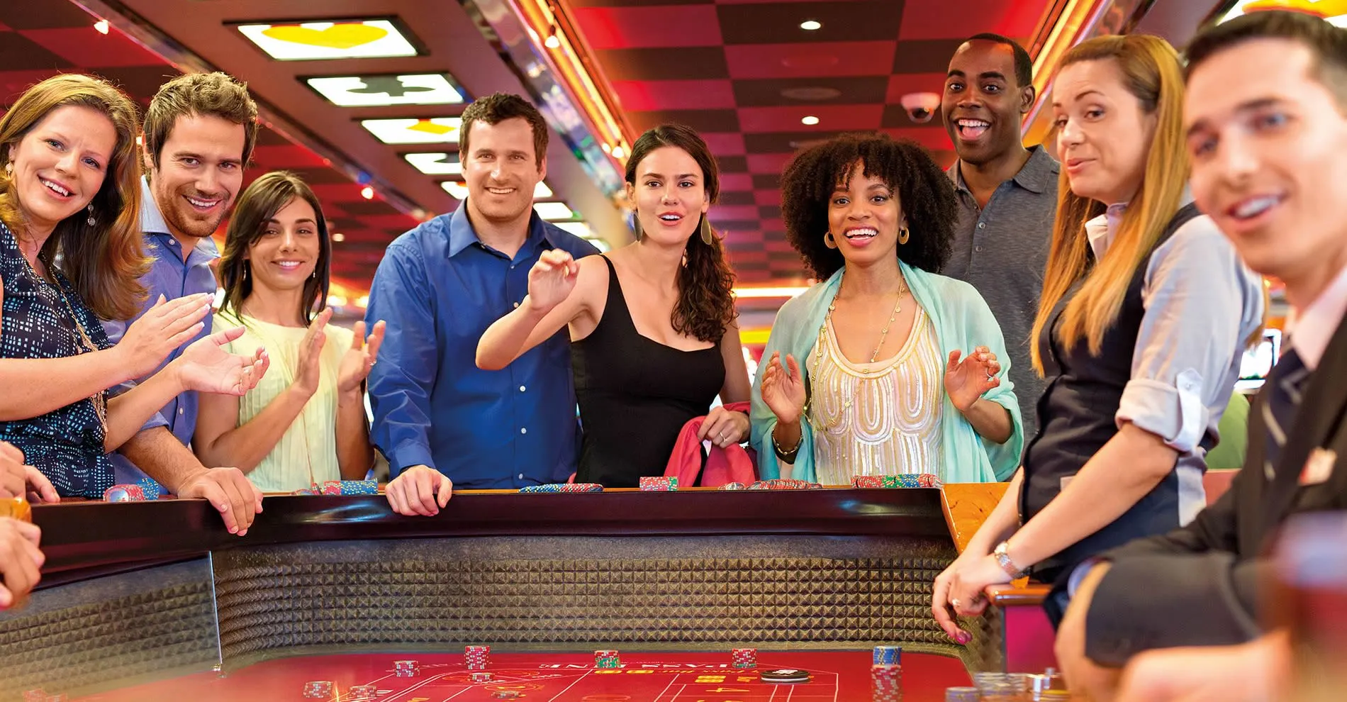 Diverse group of excited people playing together at a casino roulette table