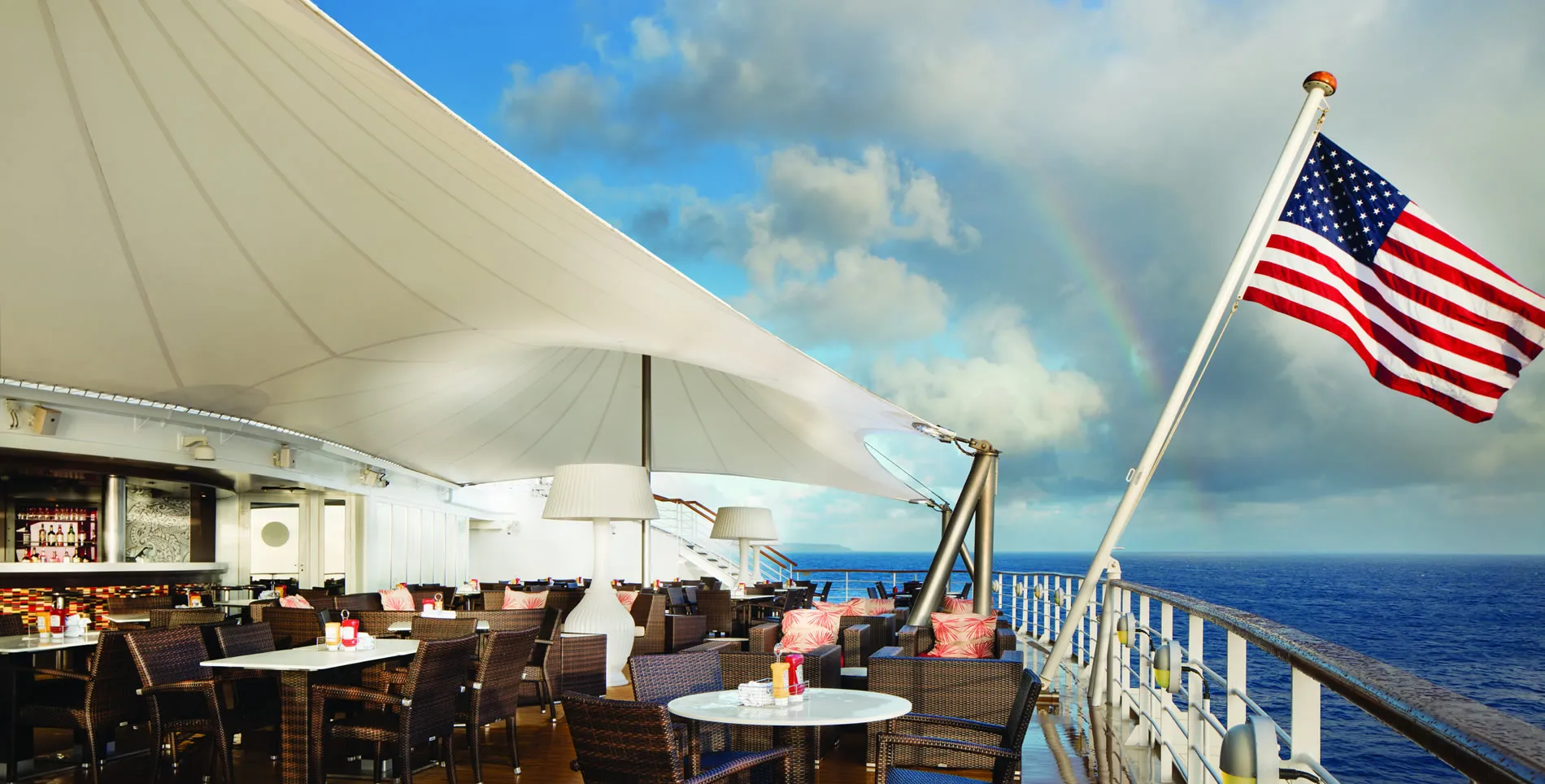 Cruise ship deck with American flag, ocean view, and empty dining area