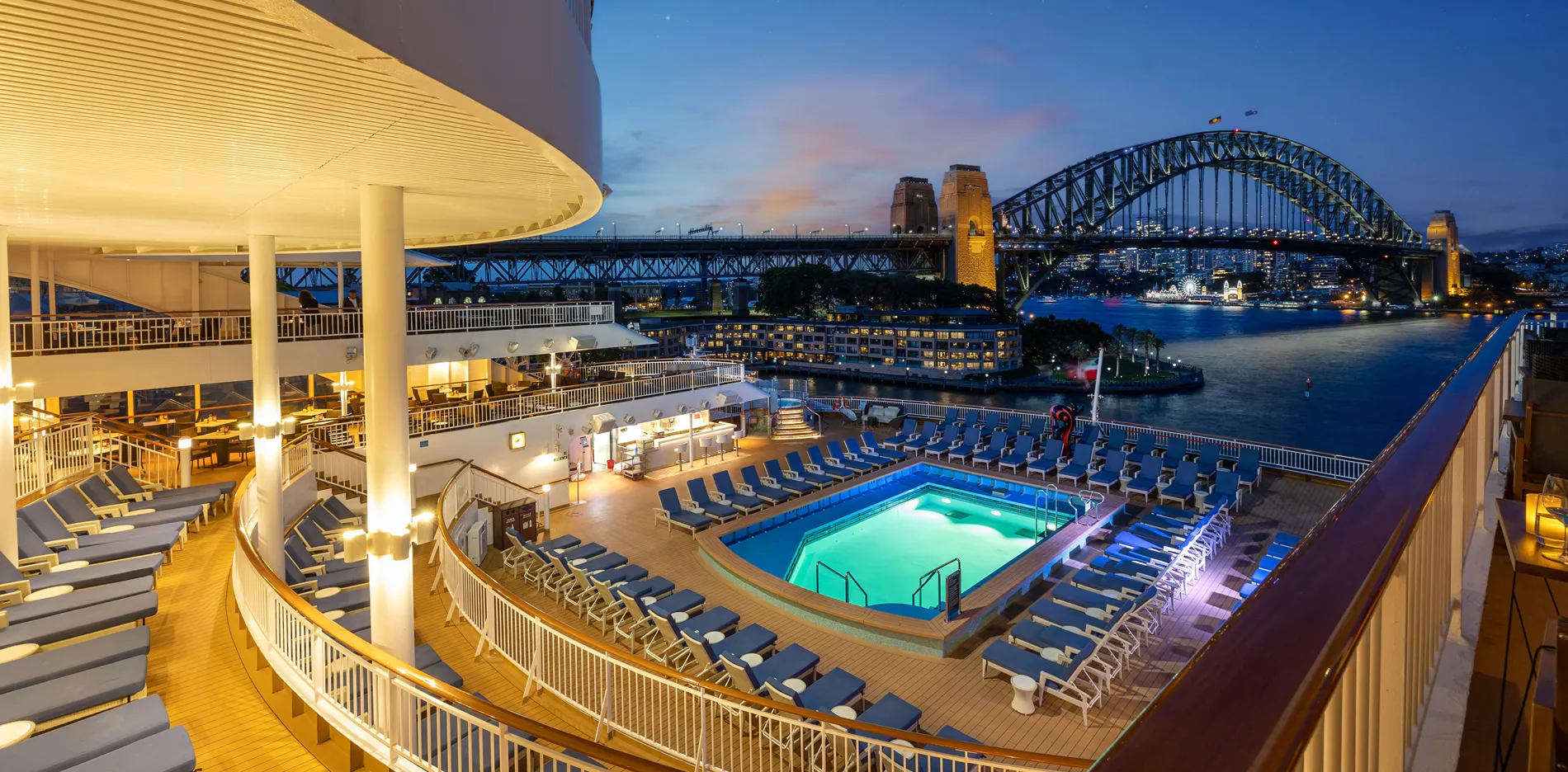 Cruise ship deck with pool overlooking Sydney Harbour Bridge at twilight