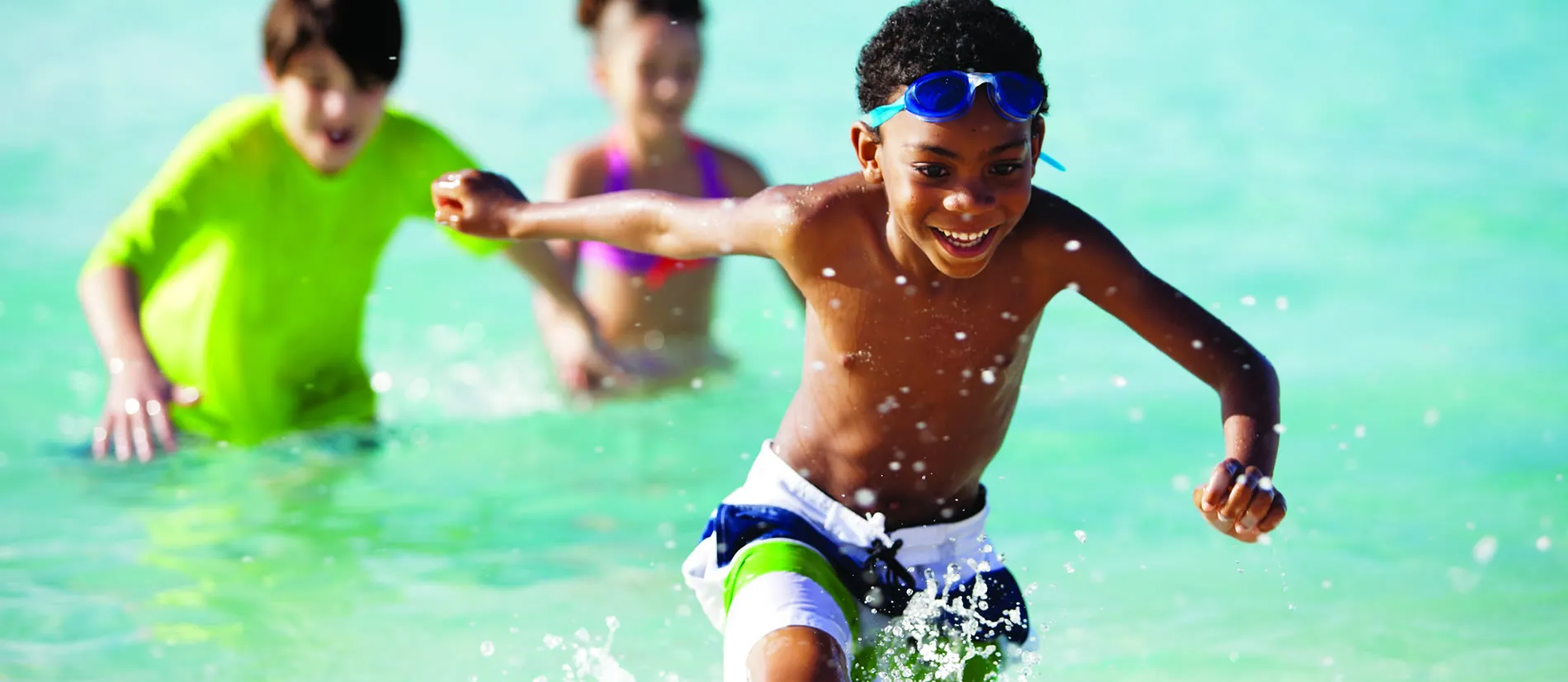 Children playing and splashing in bright turquoise swimming pool