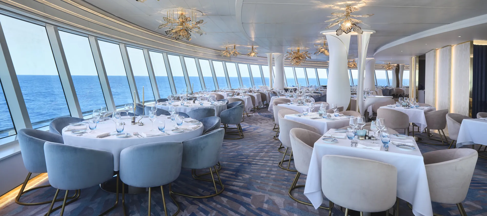 Elegant cruise ship dining room with ocean view and white-clothed tables