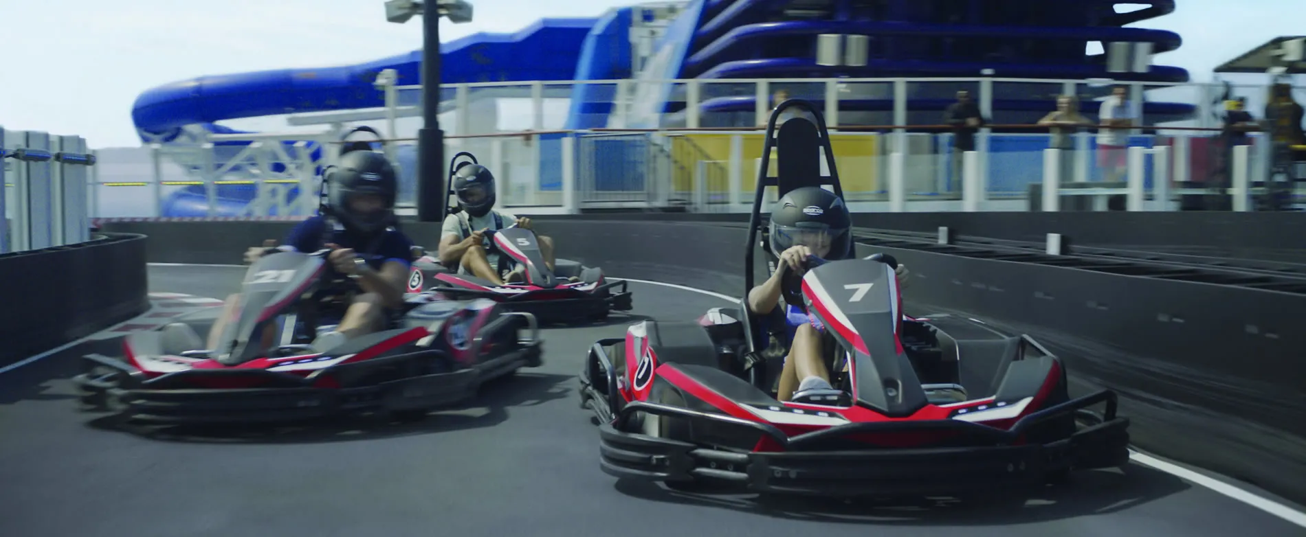 Go-karts racing on indoor track with blue water slides in background