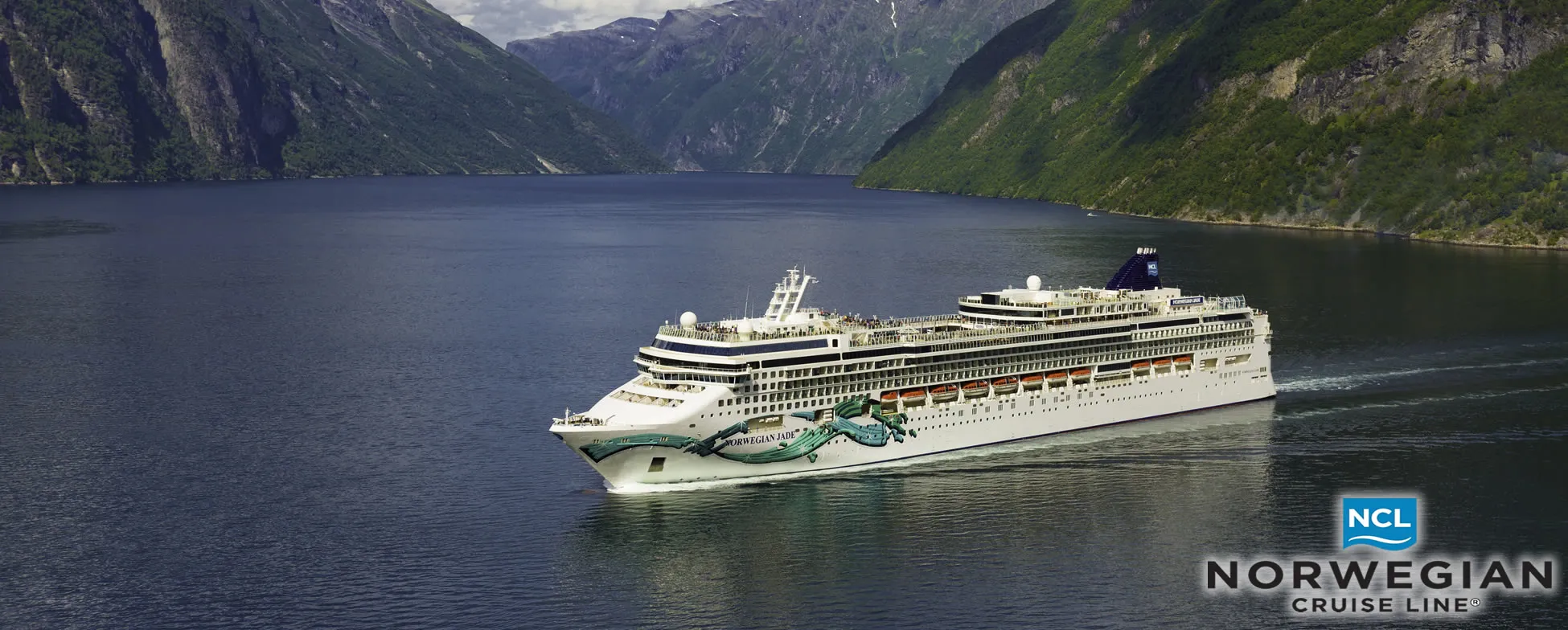 Norwegian Cruise Line ship sailing through scenic fjord with mountains