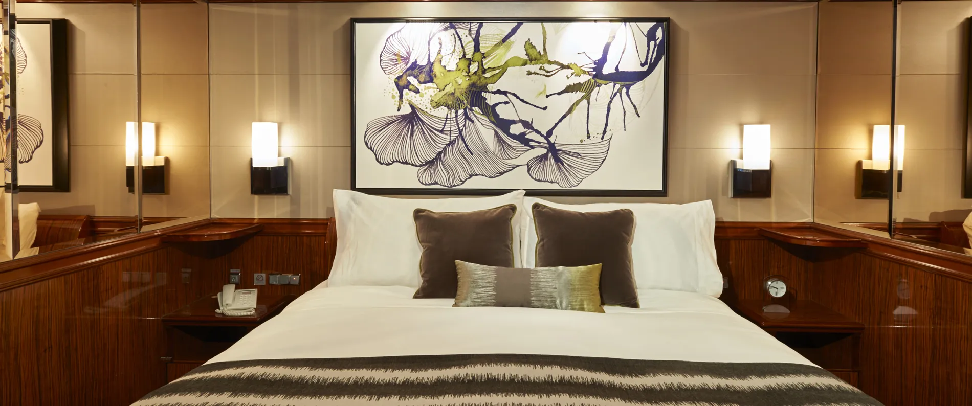 Elegant hotel bedroom with abstract floral artwork above white bed