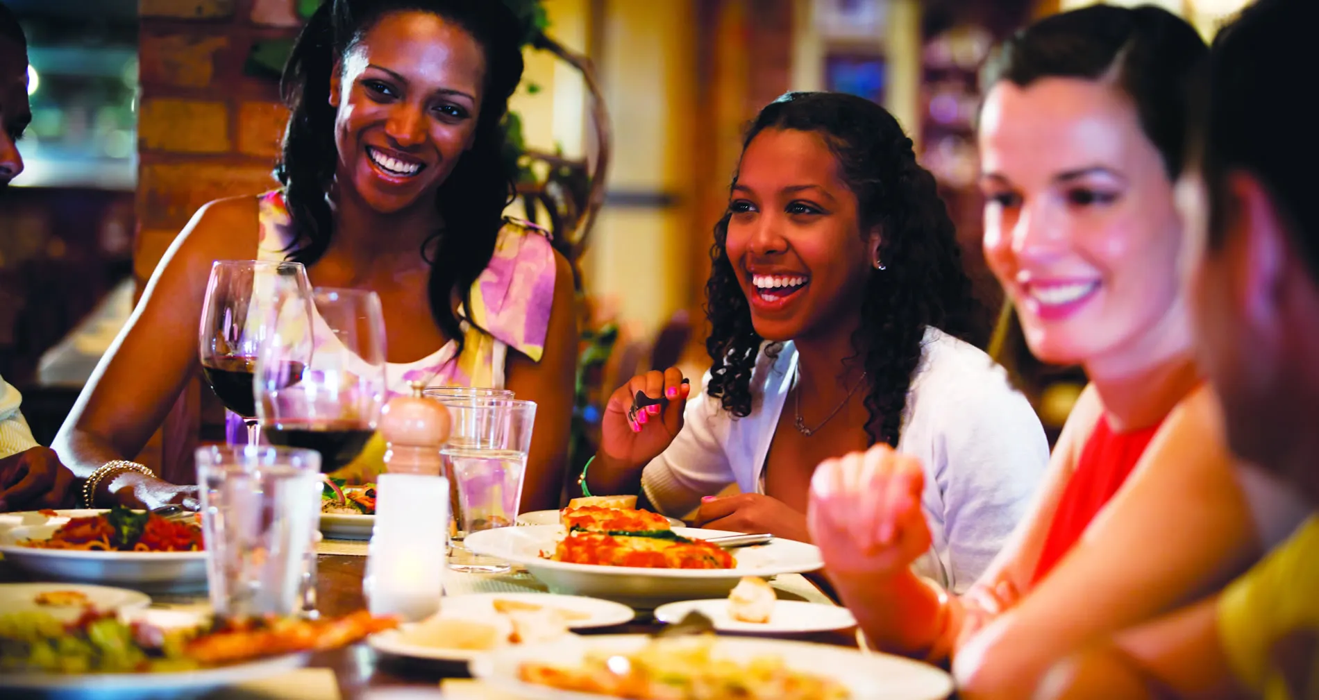 Women laughing and enjoying meal together at restaurant with wine