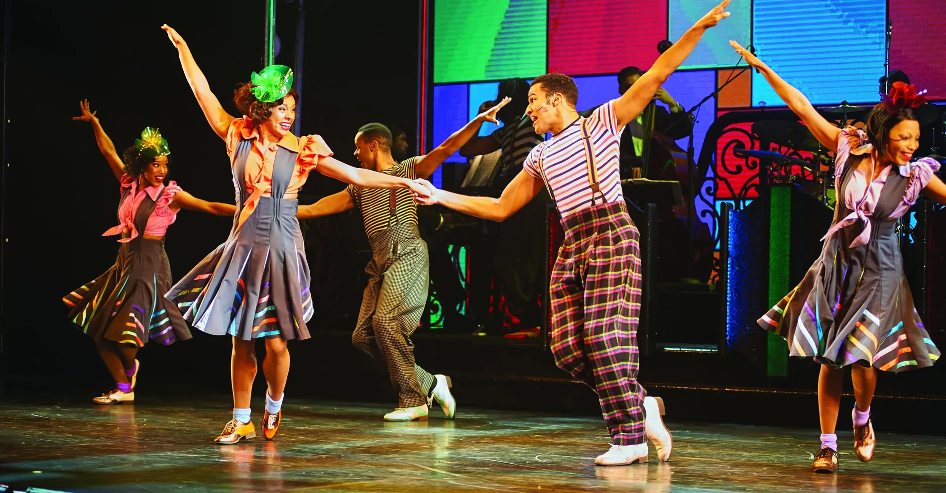 Vibrant Broadway musical dancers performing energetic choreography on stage