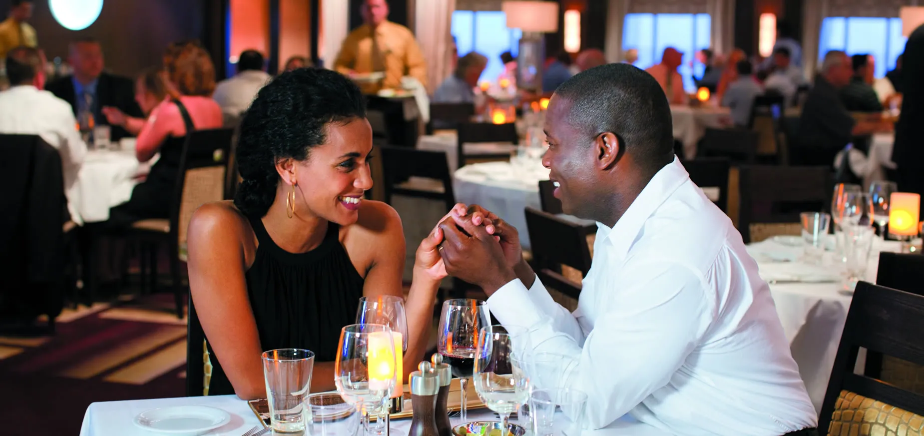 Couple on romantic date holding hands at candlelit restaurant table