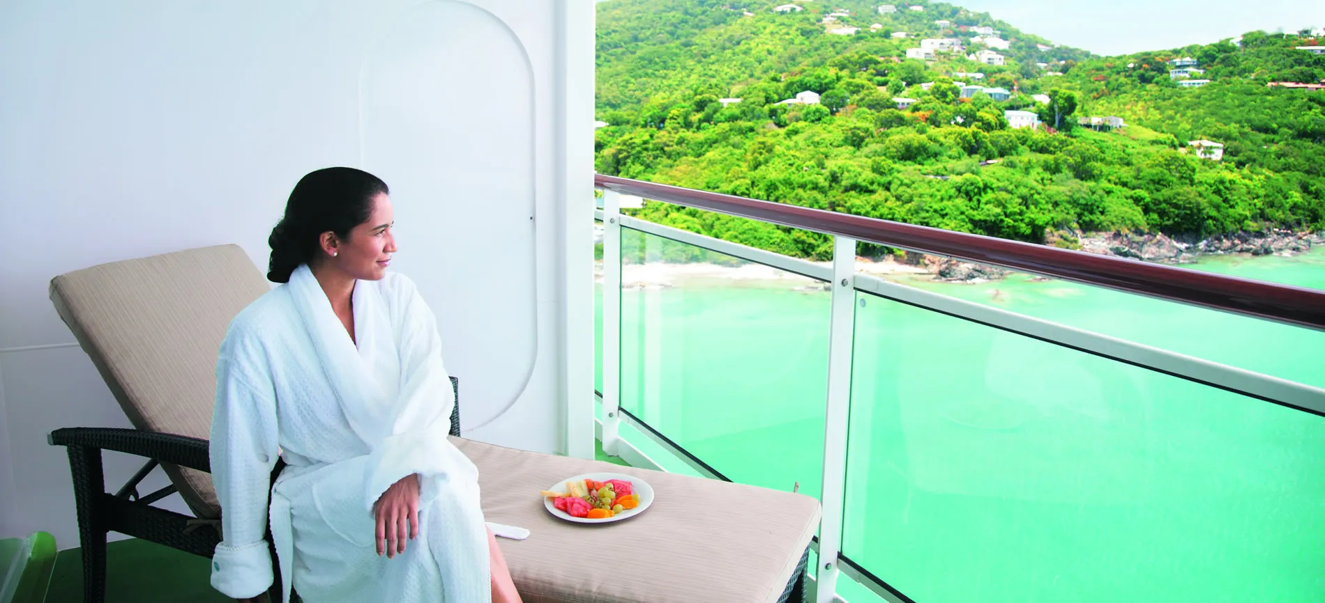 Person in white bathrobe relaxing on balcony with tropical ocean view