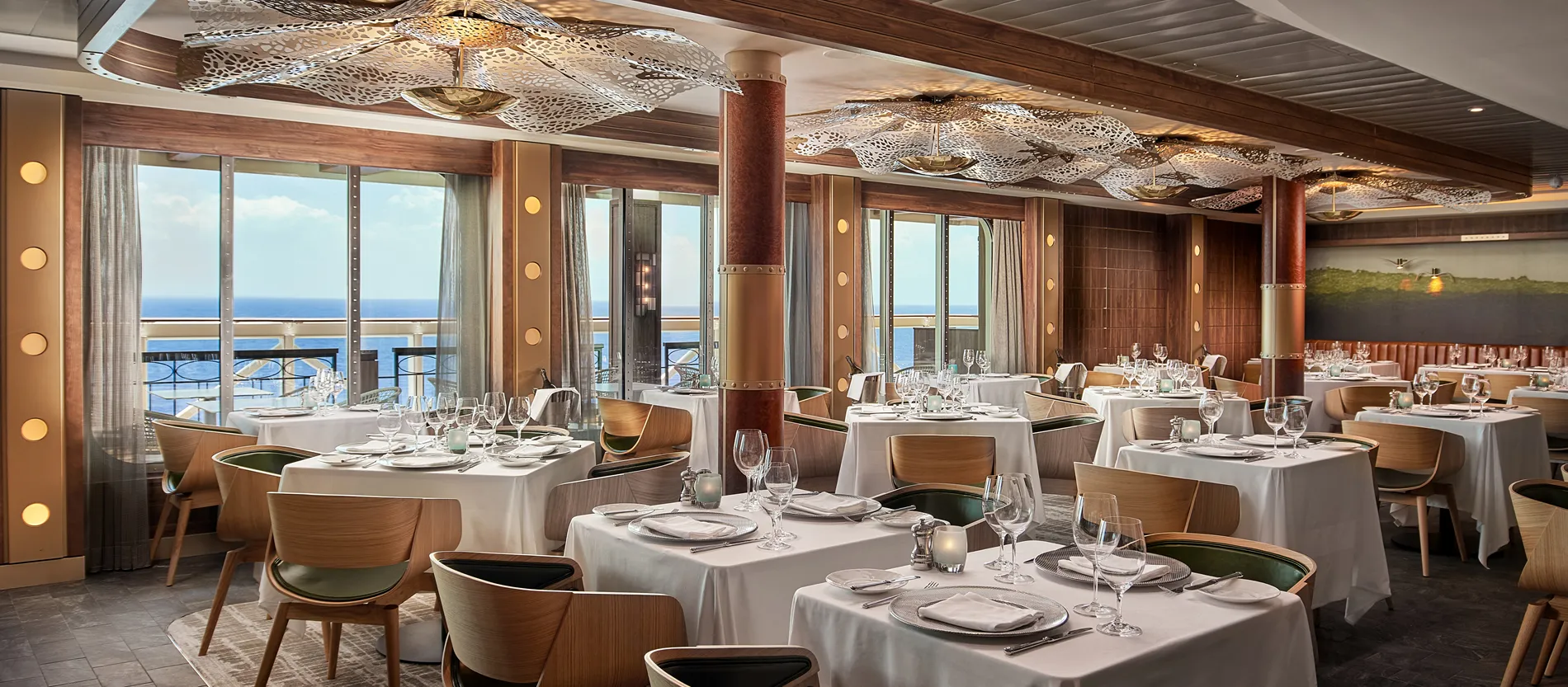 Elegant ocean-view restaurant with white tablecloths and intricate ceiling design