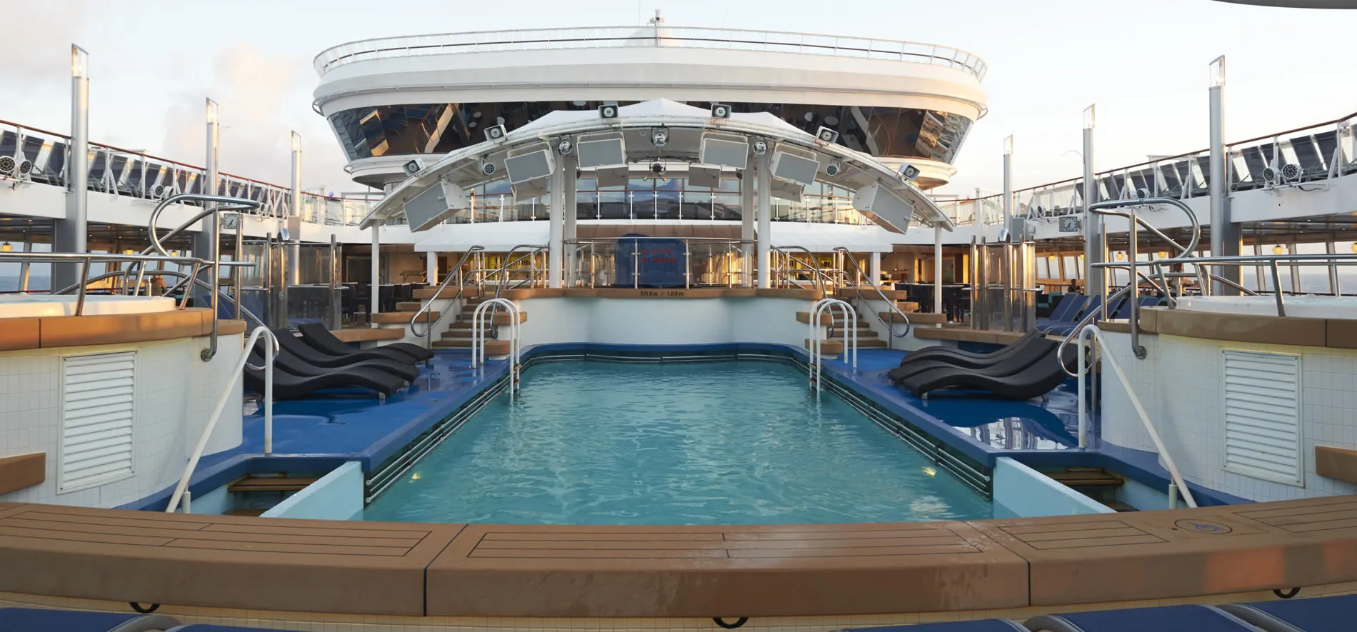 Luxurious cruise ship pool deck with blue water and lounge chairs