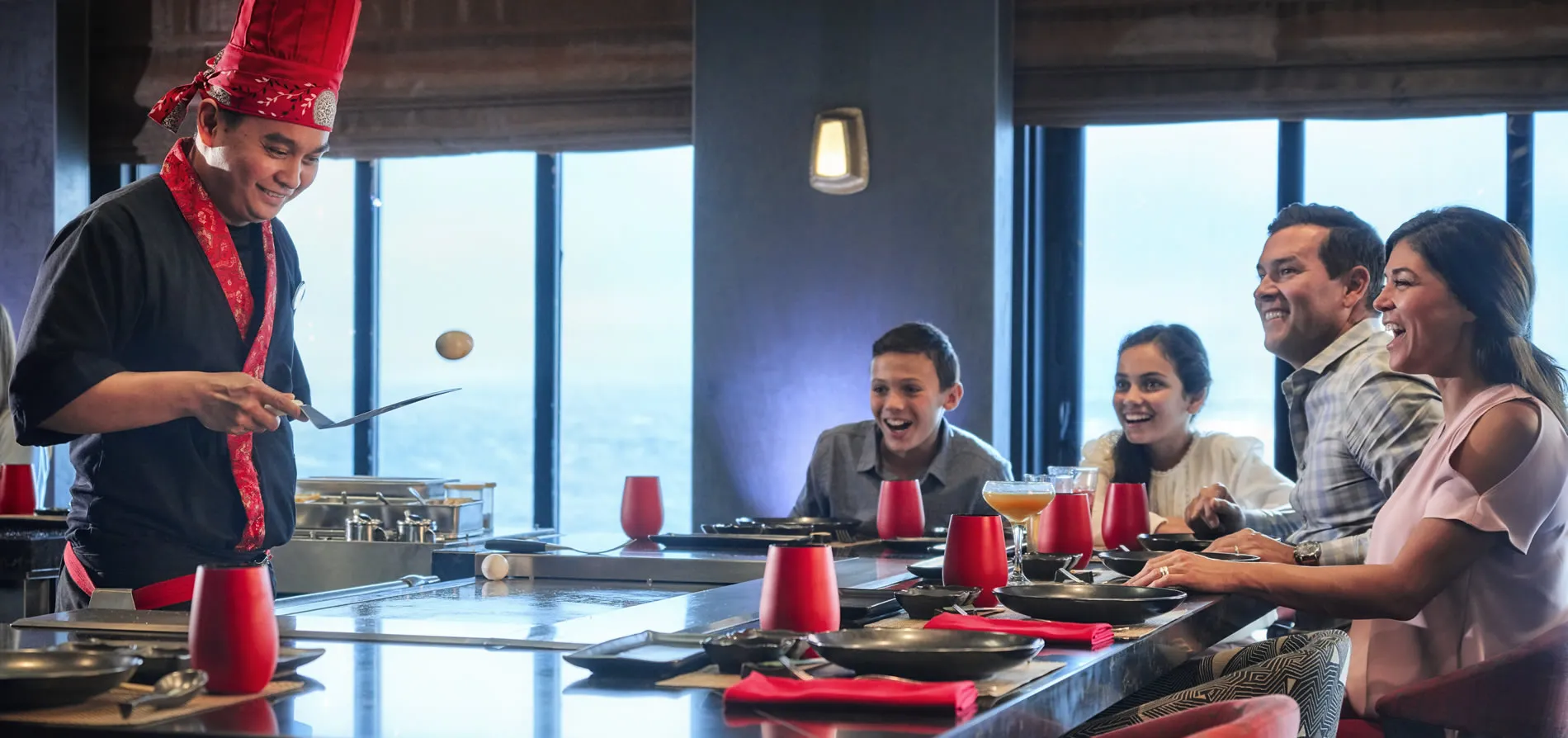 Chef in red hat entertaining family with interactive cooking performance