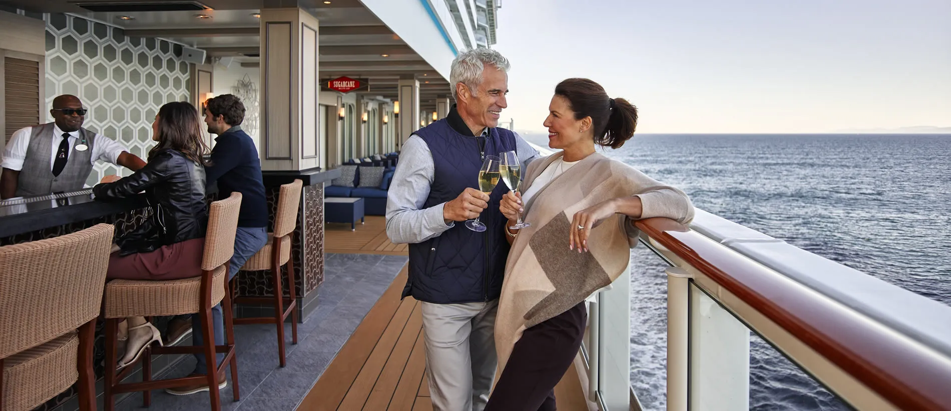 Couple toasting champagne on cruise ship deck with ocean view
