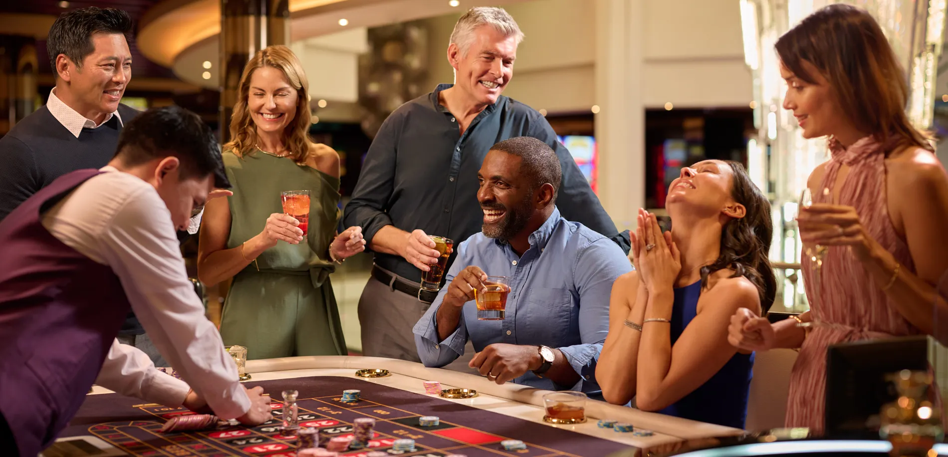 Diverse group of friends enjoying drinks and playing roulette at casino